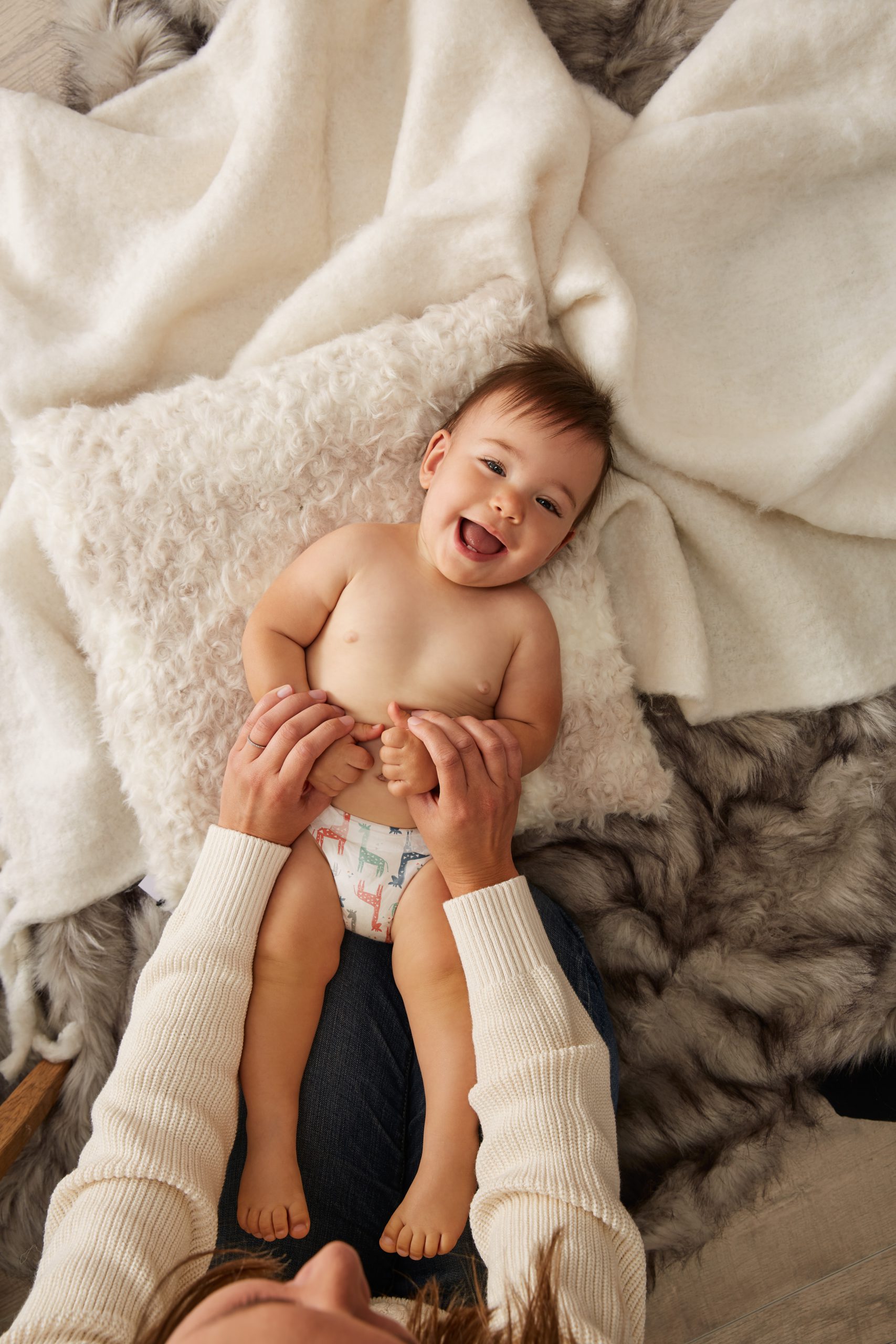 toddler smiling while lying on white pillow